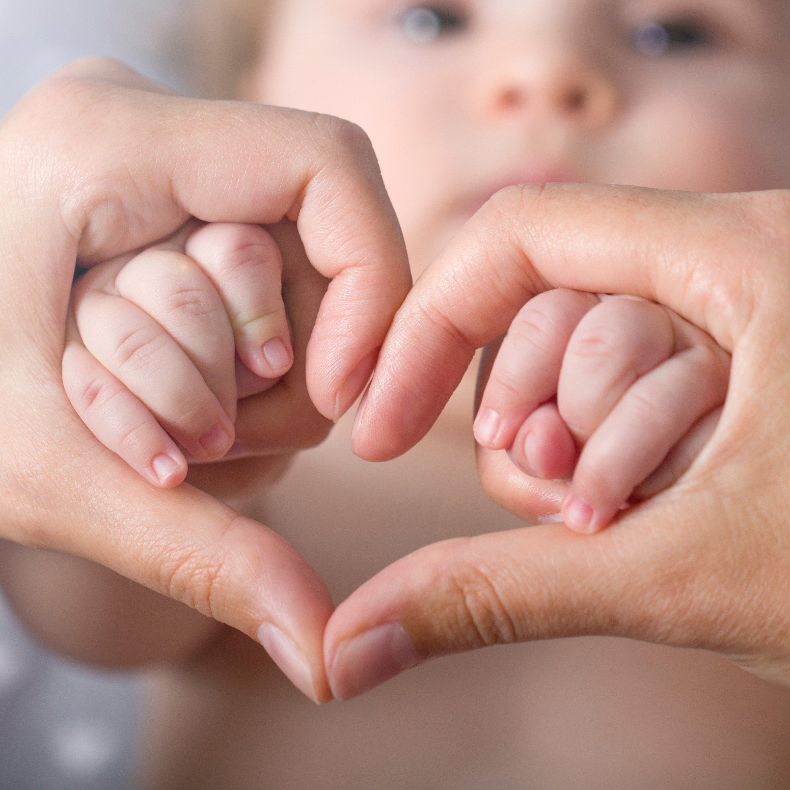 Mother holding babies hands in a heart shape