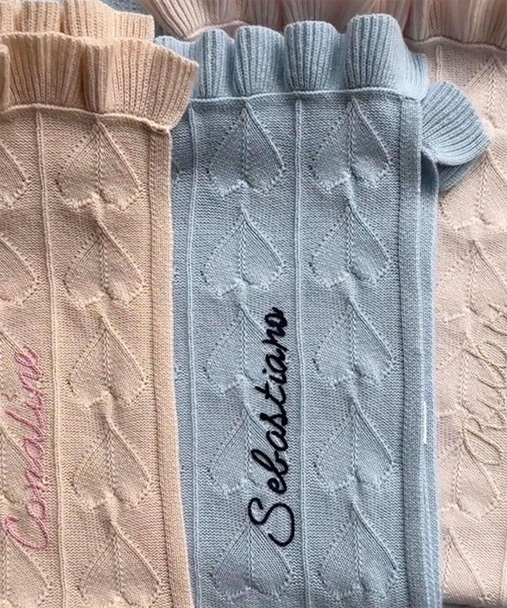 Collection of three AU Baby Little Love blankets with hand embroidered babies' names. Butter Cream, Hydrangea and Cloud colored organic cashmere blankets with heart and ruffle details.