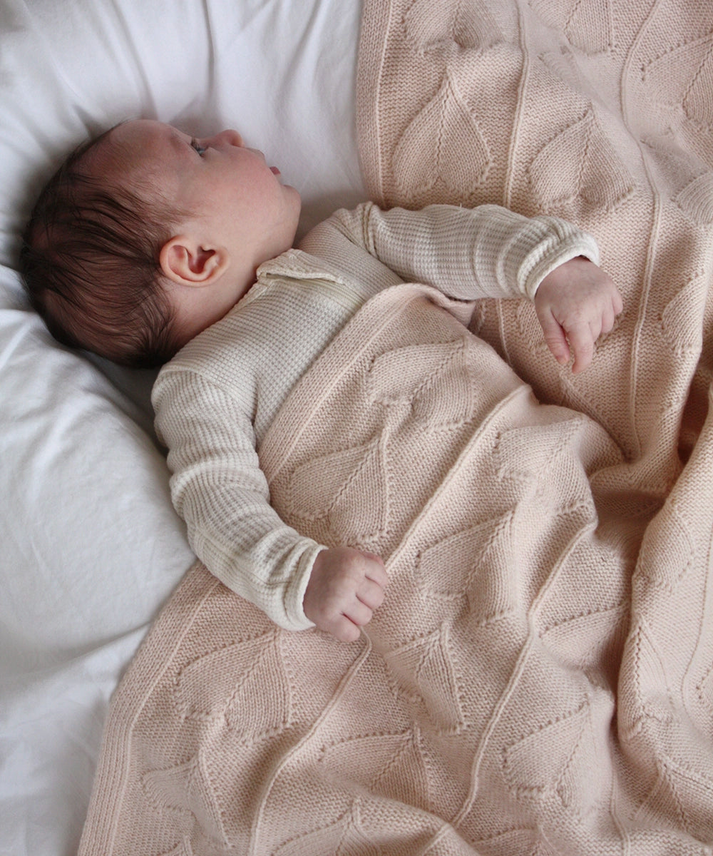 Baby snuggled up with her organic cashmere AU Baby Little Love blanket in Butter Cream.