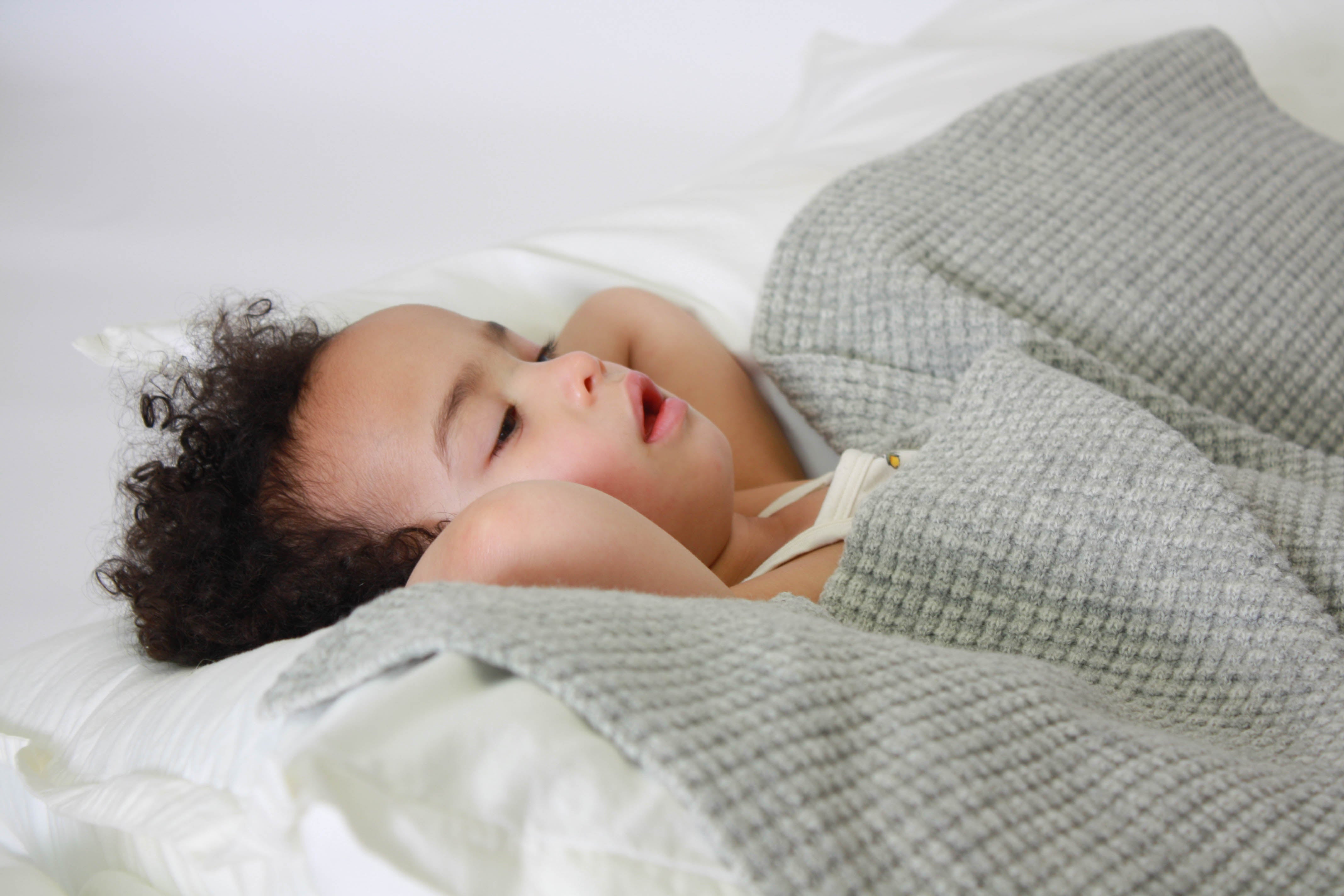 LIttle girl relaxing with the AU Baby plant dyed merino Popcorn blanket in Moonstone Grey.