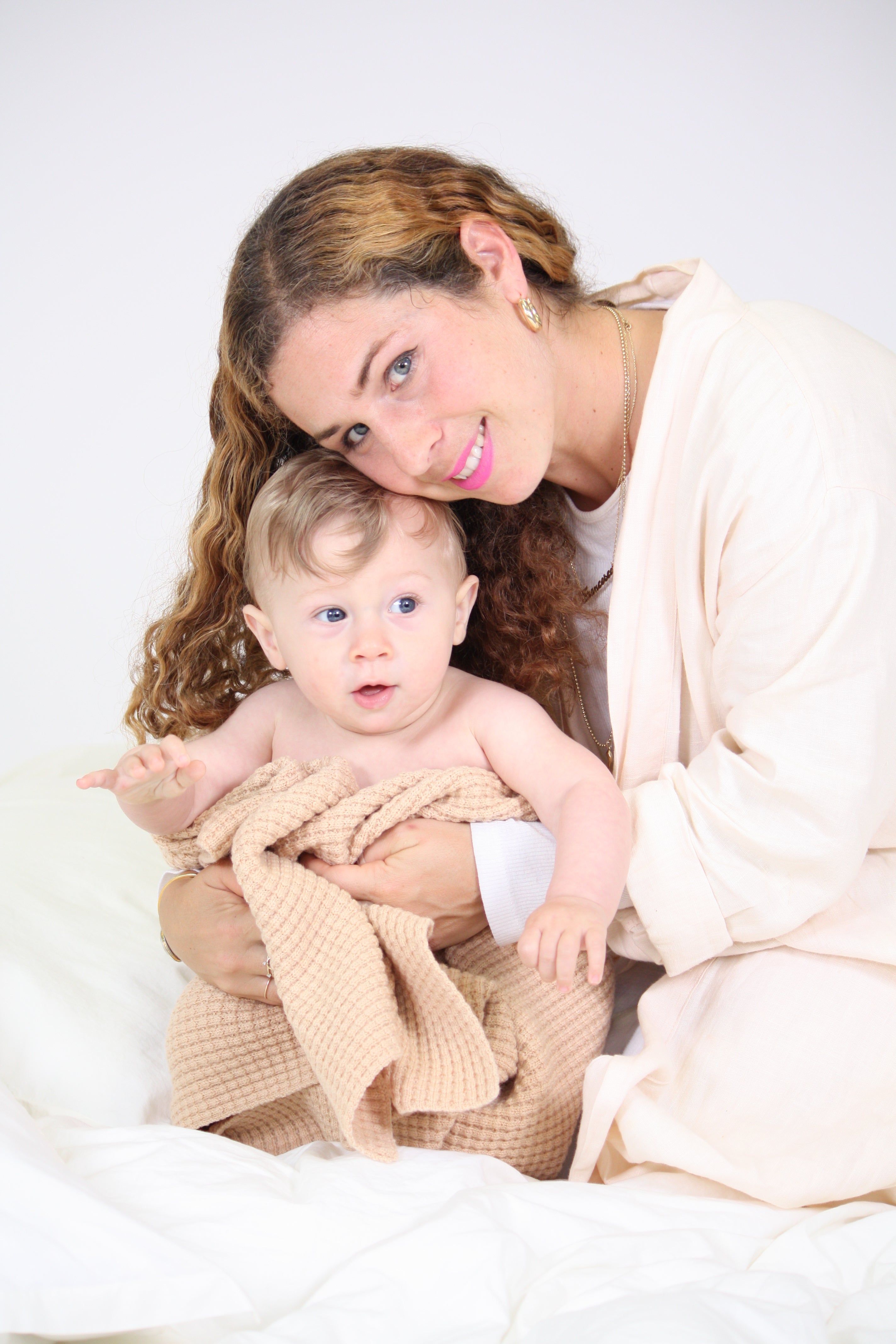 Mom and baby boy snuggling with AU Baby Popcorn blanket in Henna.